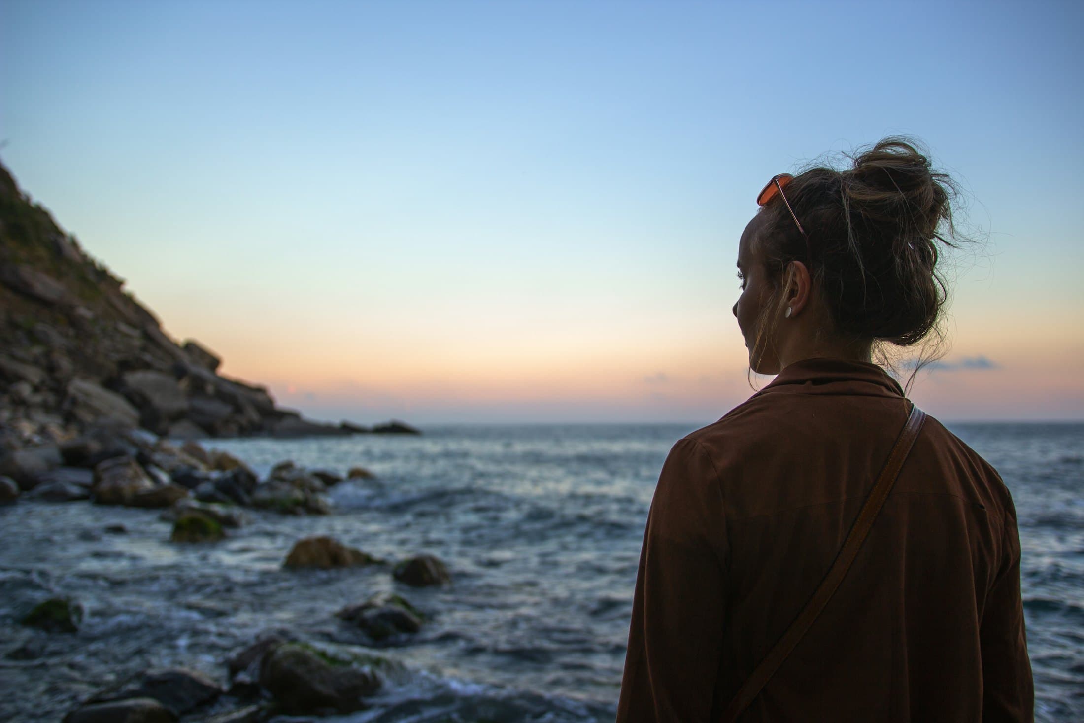 A traveller looking out to sea at sunset